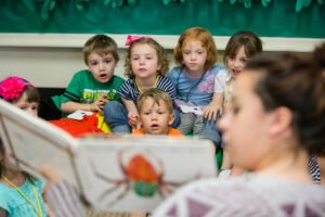 IM体育平台 Education Program student reading book to small children