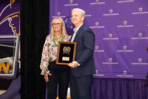 Ms. Debbie Jones receiving her award from President Bruntmyer on stage.